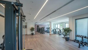 Un gimnasio moderno con equipamiento de ejercicio, suelo de madera y ventanas amplias.