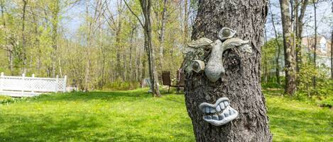 A tree with a carved face and a handprint, surrounded by a grassy area and trees.