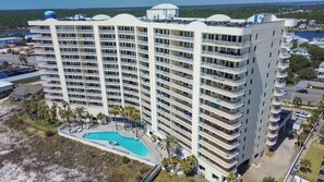 A high-rise hotel with multiple balconies, a swimming pool, and a view of the surrounding landscape. - Beachfront Panoramic Gulf Views Admirals Quarters 306 (Orange Beach)