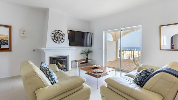 A living room with a fireplace, a TV, and a balcony with a view of the sea. - Apartment do Ramses with oceanviews (Luz)