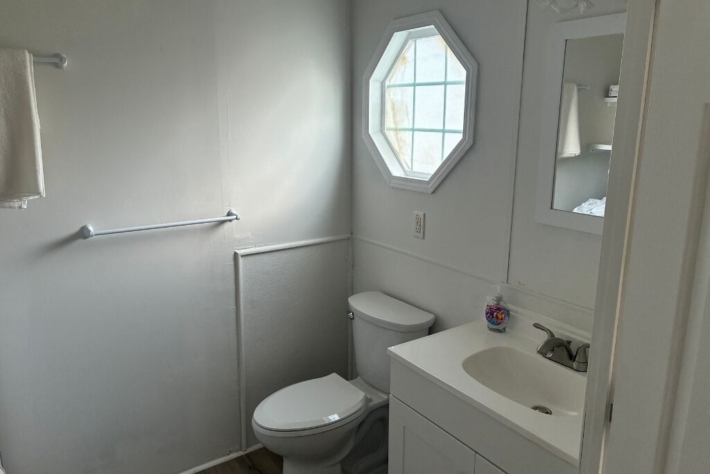 Ein kleines Badezimmer mit Toilette, Waschbecken und Fenster.