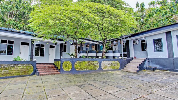 A courtyard with a central tree, surrounded by buildings with steps leading to a door. - OYO 92287 Hotel Aji Mantoro (Belik)