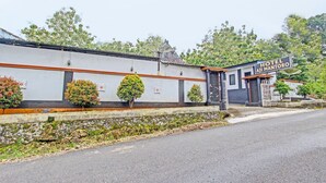 A hotel named "Hotel Aji Mantoro" with a traditional architectural style, featuring a stone wall and a small entrance gate. - OYO 92287 Hotel Aji Mantoro (Belik)