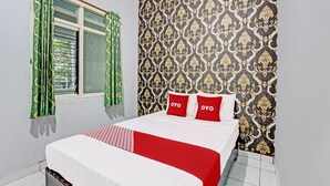 A bedroom with a bed, green curtains, patterned wallpaper, and a window with blinds. - OYO 92287 Hotel Aji Mantoro (Belik)