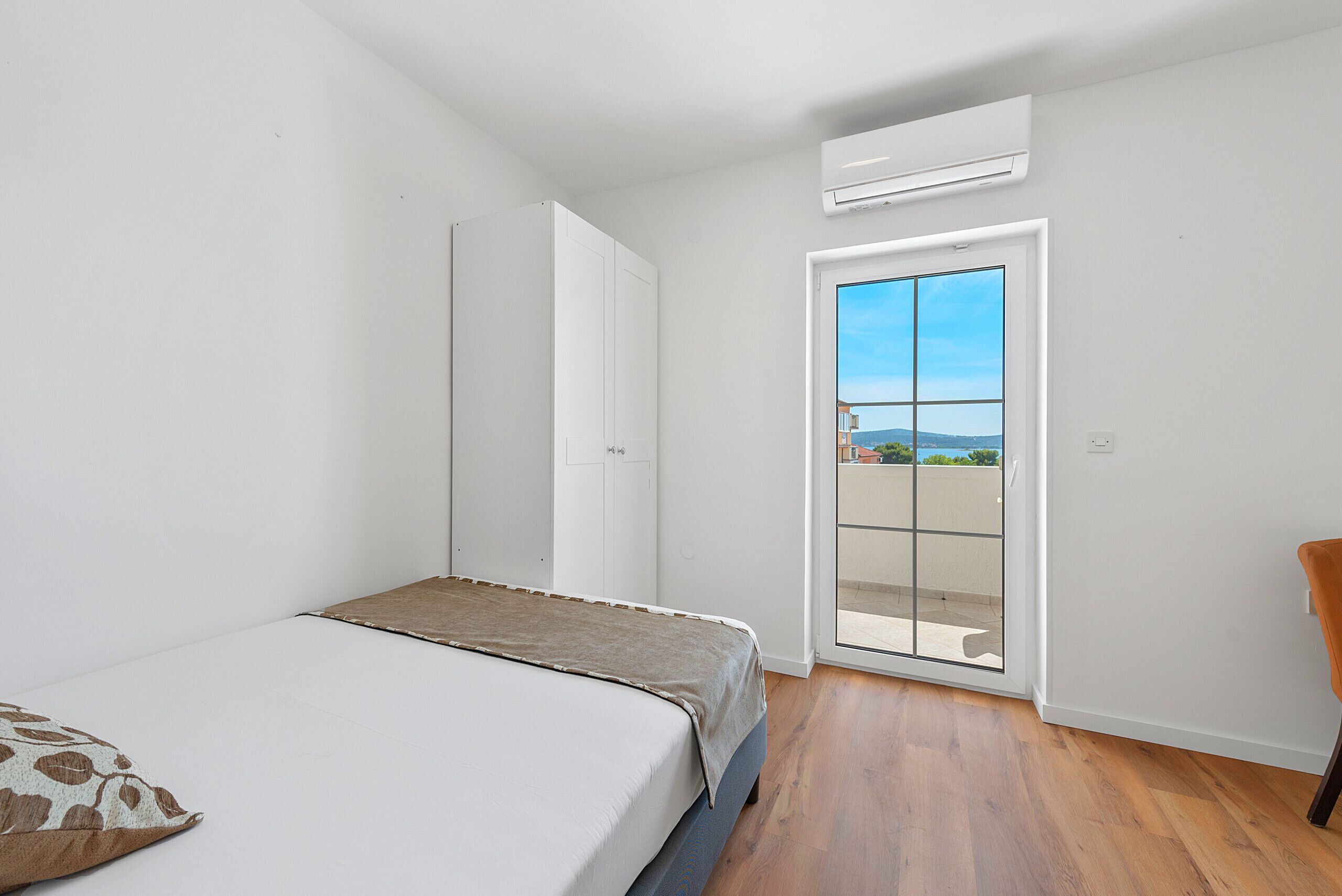 Un dormitorio con cama, armario y puerta corrediza de vidrio a un balcón.