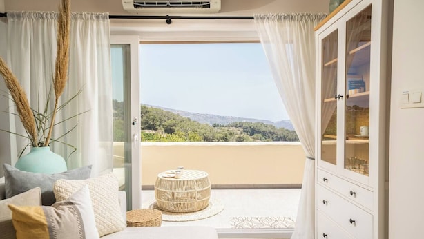 A balcony with a view of a mountainous landscape, a wicker ottoman, and a white cabinet with glass doors. - Scenic Mountain View Escape w/ Pool & Tennis (els Castellons)