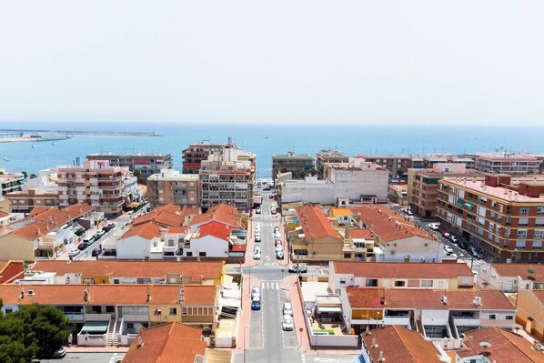 A coastal town with a central street lined with multi-story buildings, some with visible balconies.