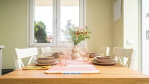 Ein Esstisch, gedeckt mit Tellern, Gläsern und einer Blumenvase.