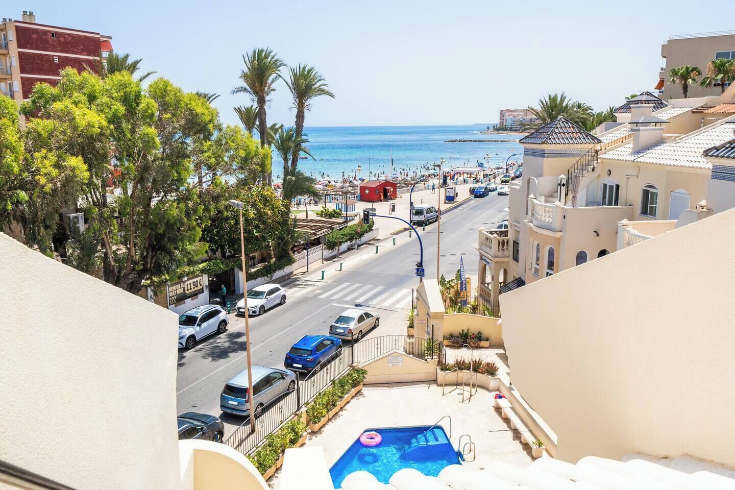 Une vue de rue avec une piscine, des palmiers et une plage en arrière-plan.