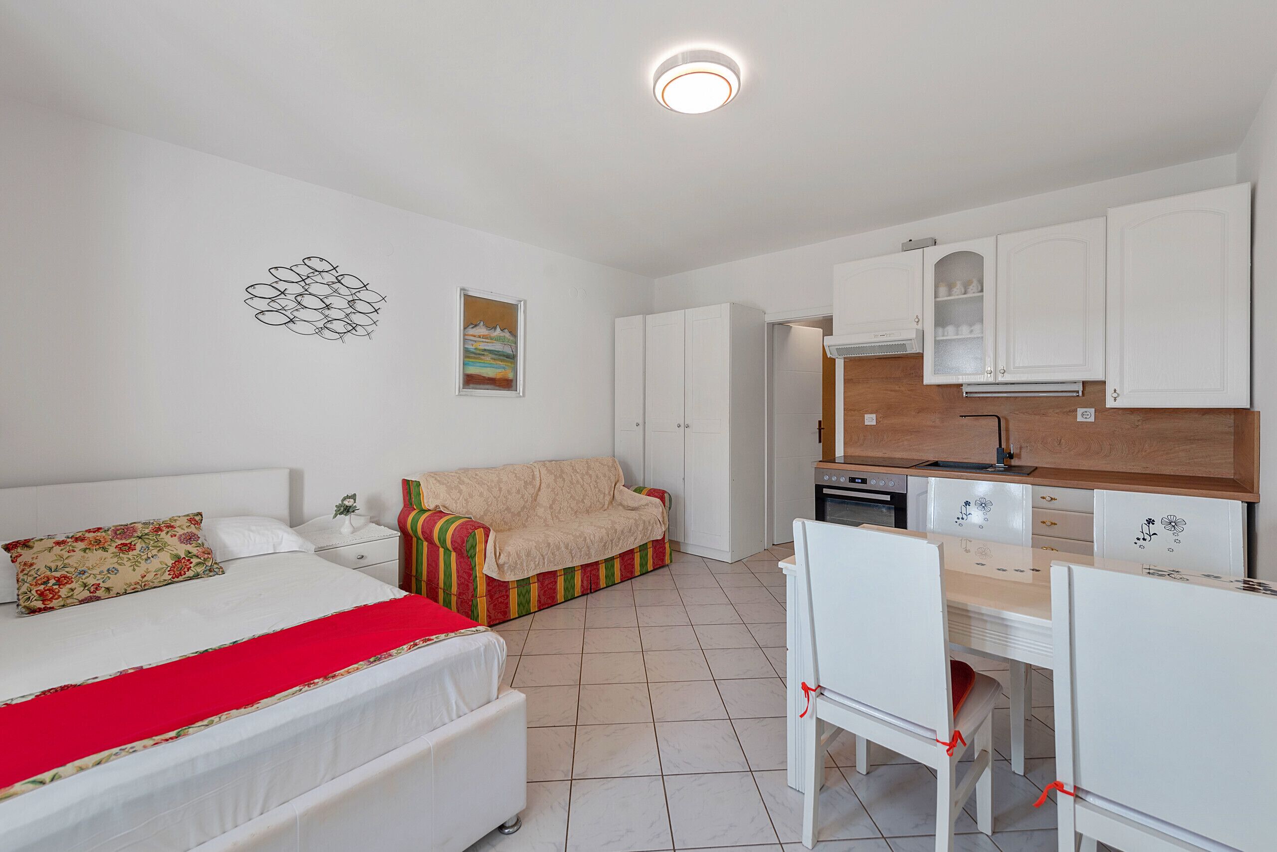 Una habitación con cama, sofá, mesa de comedor con sillas y zona de cocina.