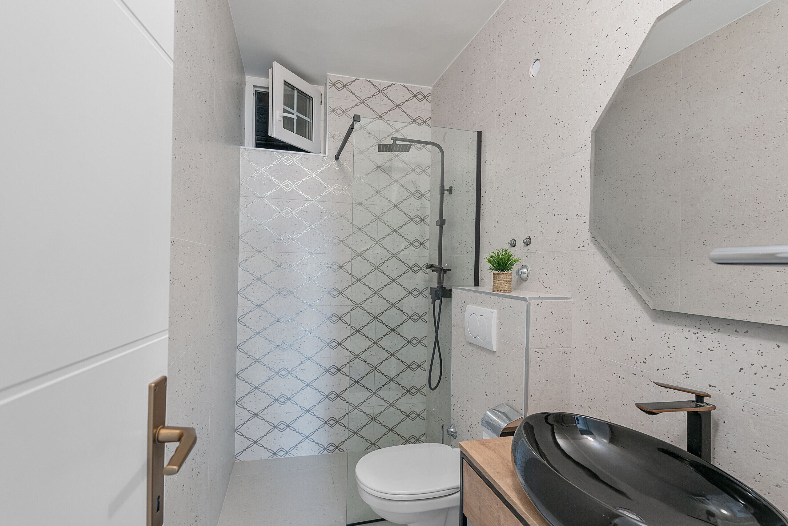 A modern bathroom with a glass-enclosed shower, a toilet, and a sink with a wooden countertop.