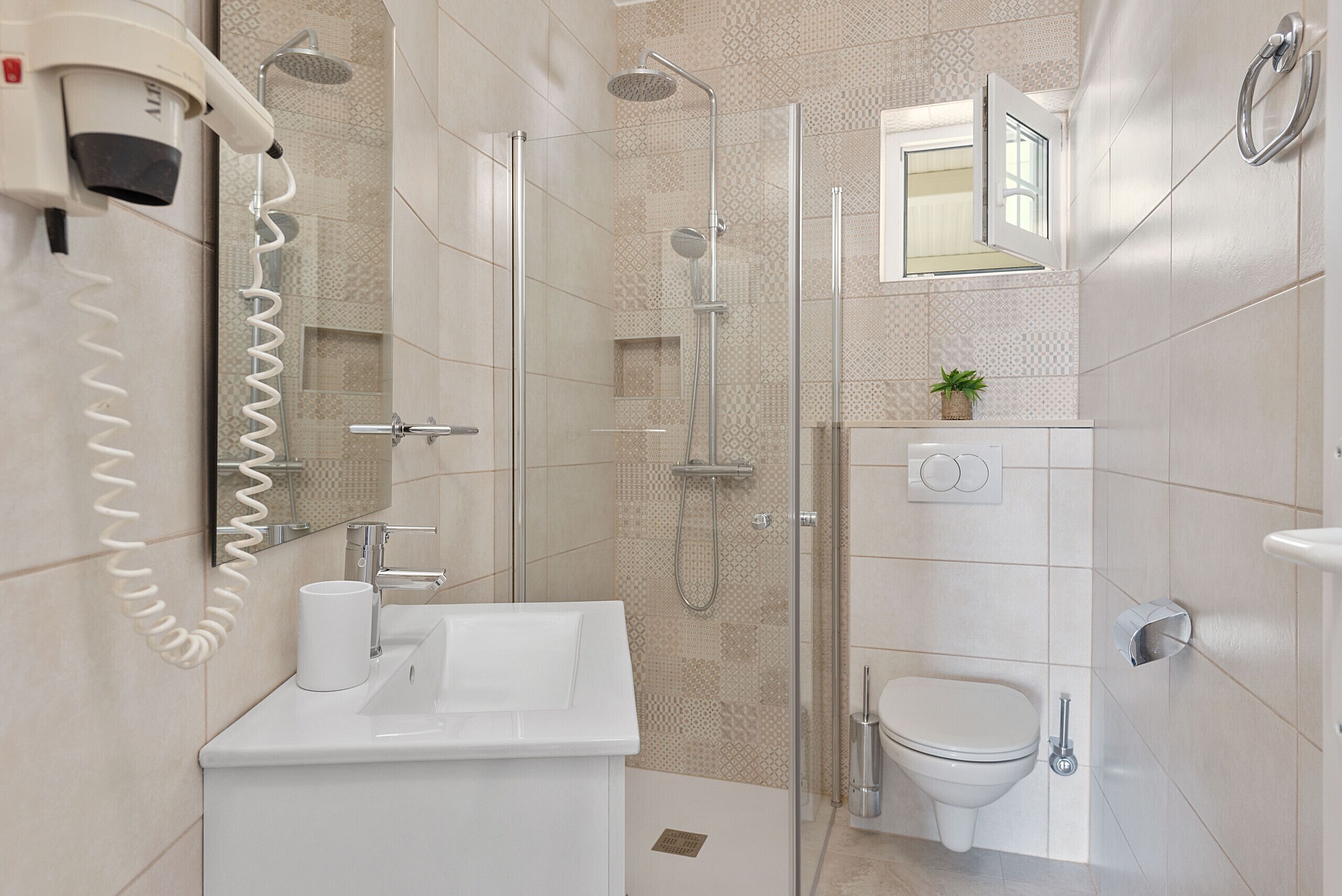 A modern bathroom with a glass-enclosed shower, a toilet, a sink, and a hairdryer.
