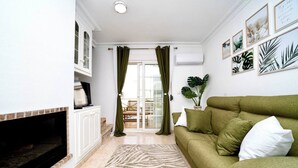 A living room with a green sofa, a fireplace, and a view to the outside.