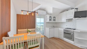 A modern kitchen with white cabinets, a built-in oven, and a TV mounted above the counter.