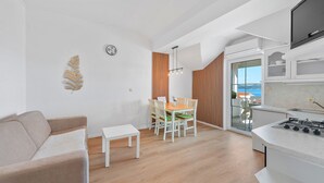 A modern kitchen with a stove, a dining area with a table and chairs, and a sofa.