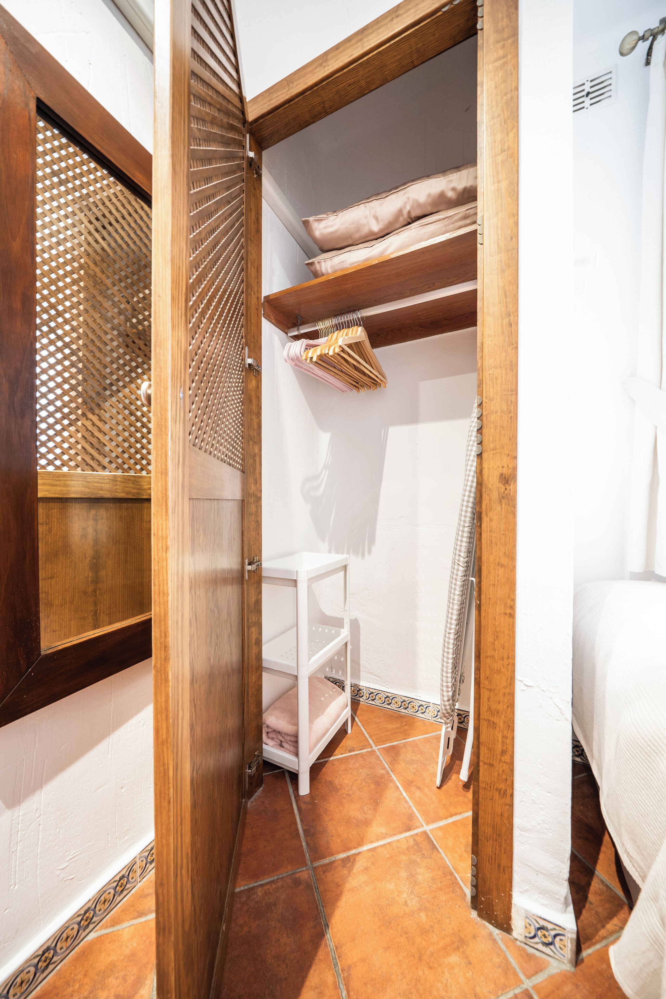 Ein kleines Badezimmer mit Holztür, weißem Ablagefach und Fliesenboden.