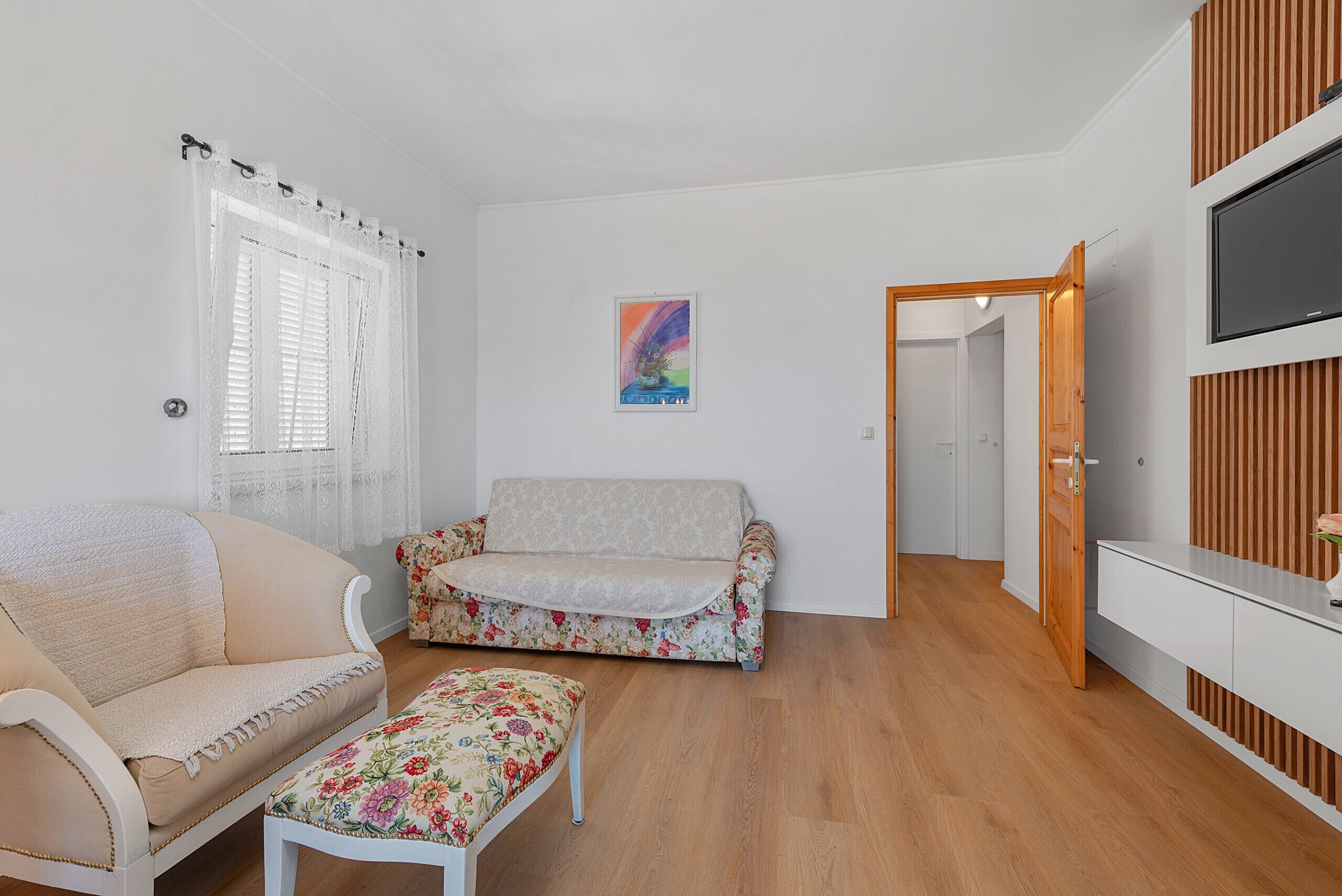 Una habitación con sofá, una mesita, televisor y puerta de madera.