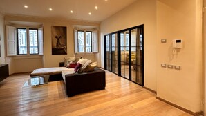 Een ruime slaapkamer met een groot bed, een bank en uitzicht door een glazen deur.