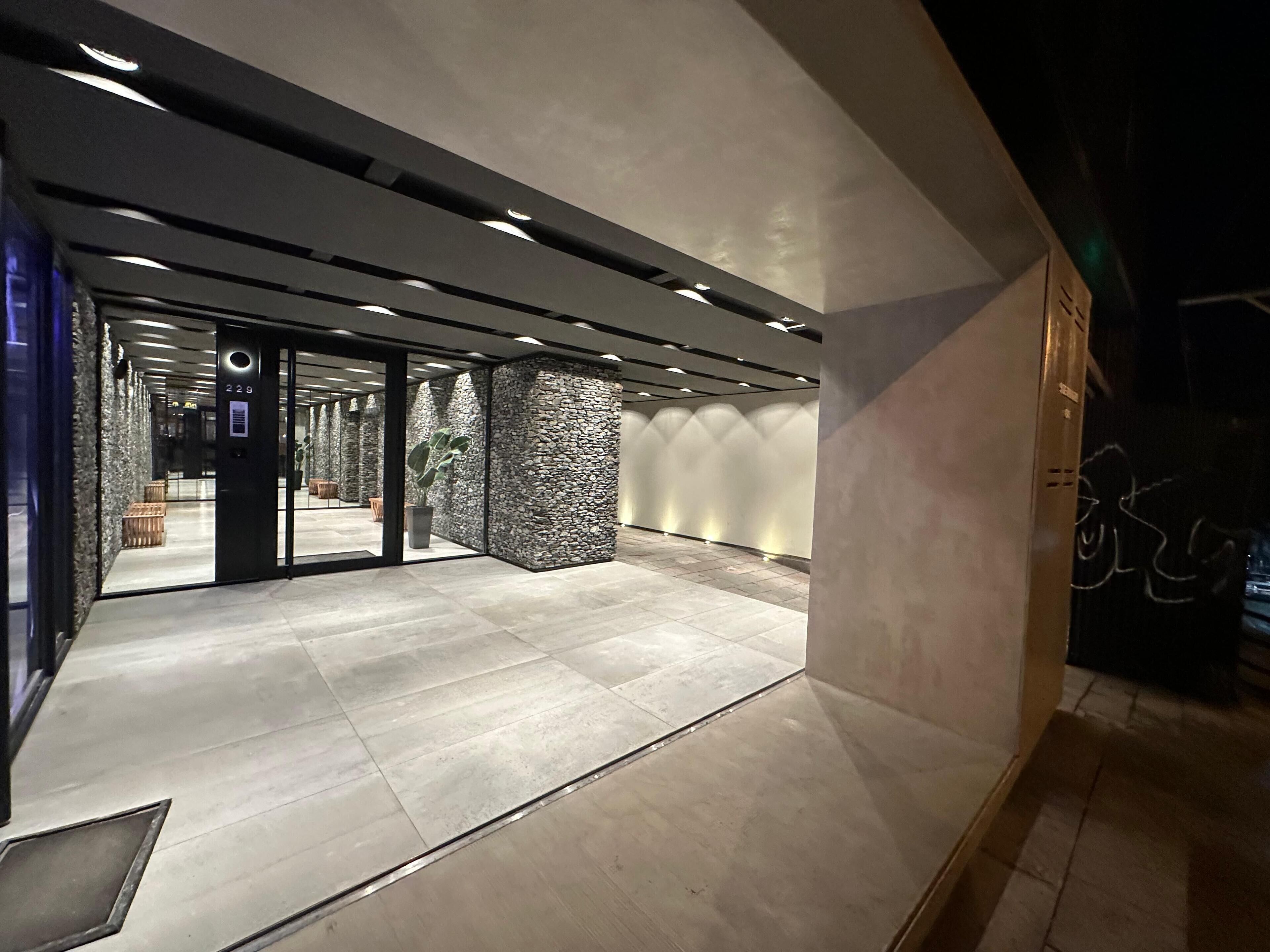 Un interior moderno con una pared de piedra, una puerta de cristal y un suelo de baldosas.