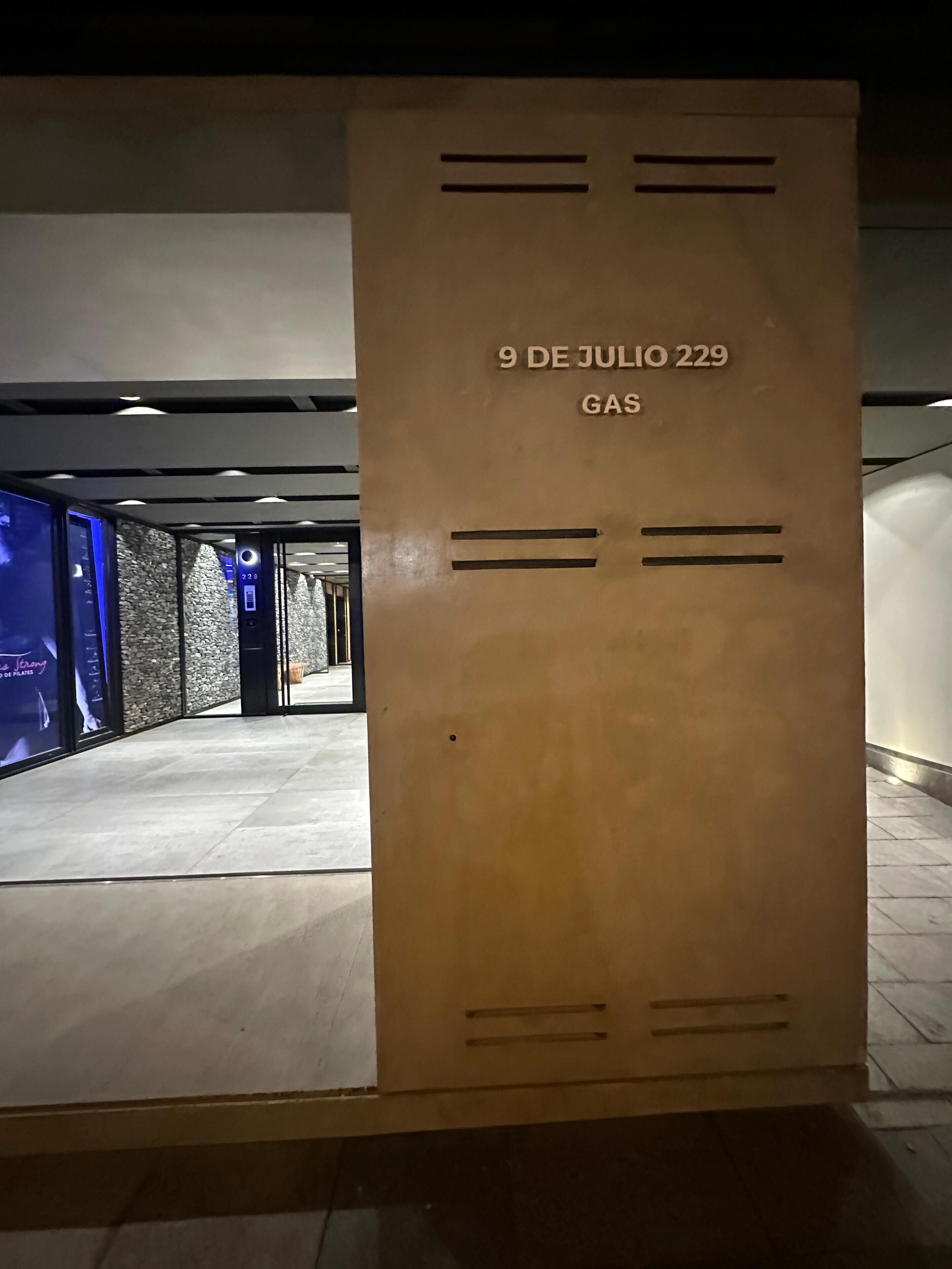 A corridor with a large wooden panel displaying the date "9 DE JULIO 229" and the word "GAS".
