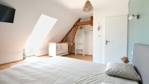 A bedroom with a sloped ceiling, a bed, a crib, and a wardrobe. - Cottage 'La Mottelette' with Private Terrace and Garden (Forest-Montiers)