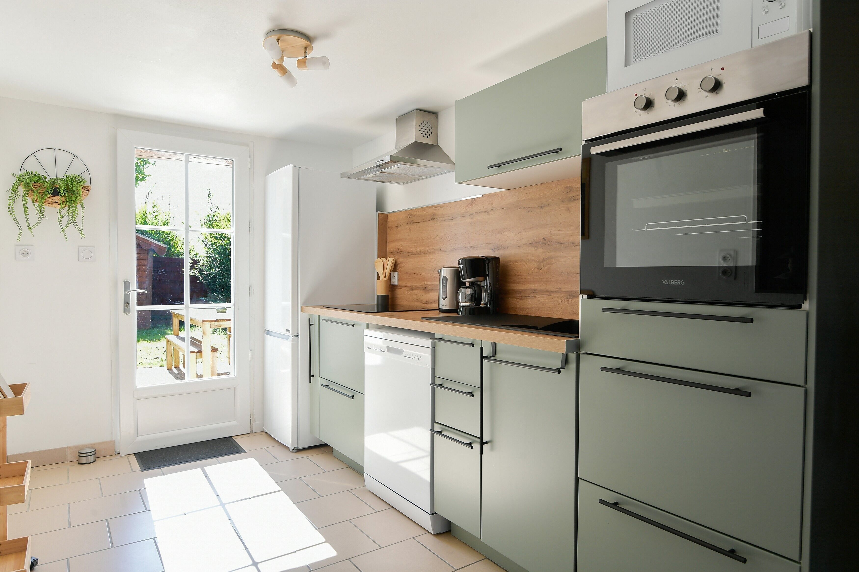 A modern kitchen with a dishwasher, oven, and a wooden countertop.