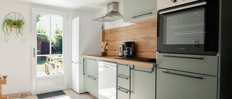 A modern kitchen with a dishwasher, oven, and a wooden countertop.