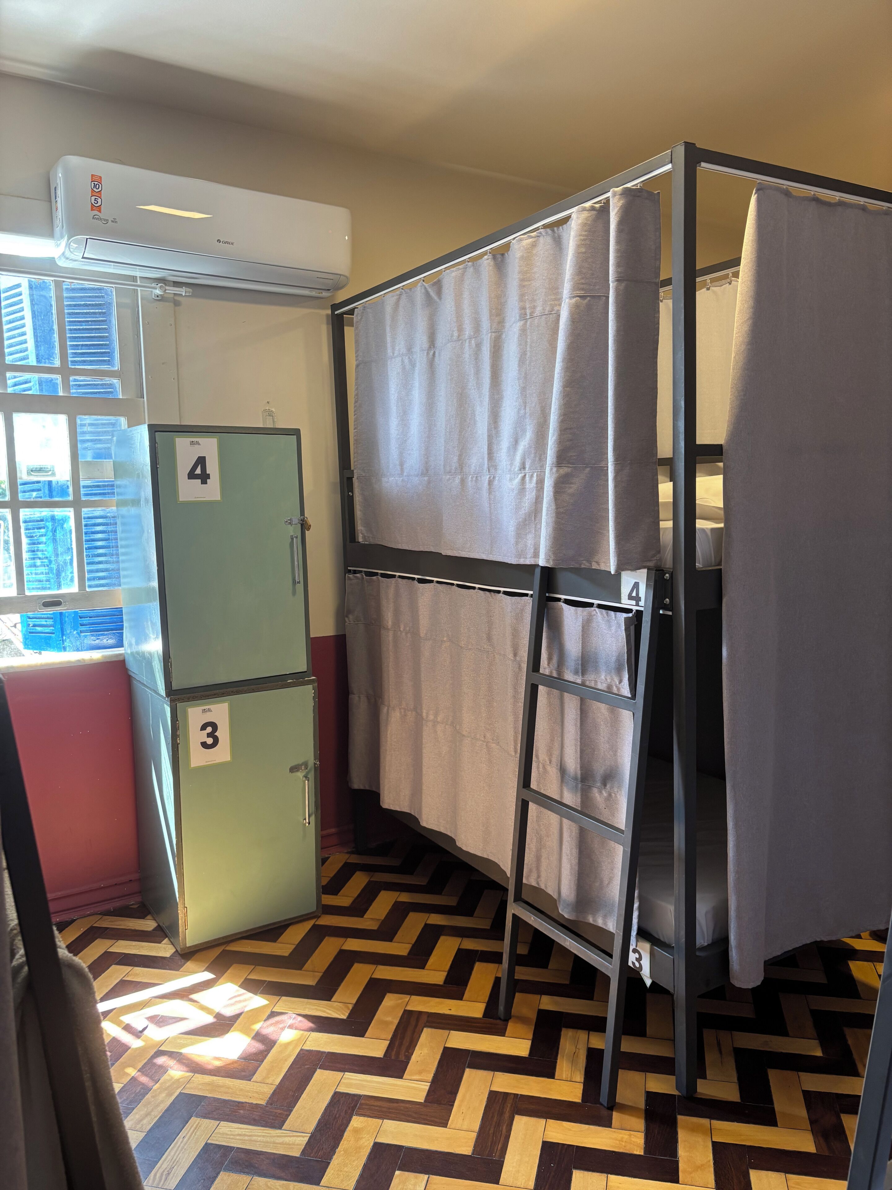A compact room with bunk beds, a kitchenette, and a patterned floor.