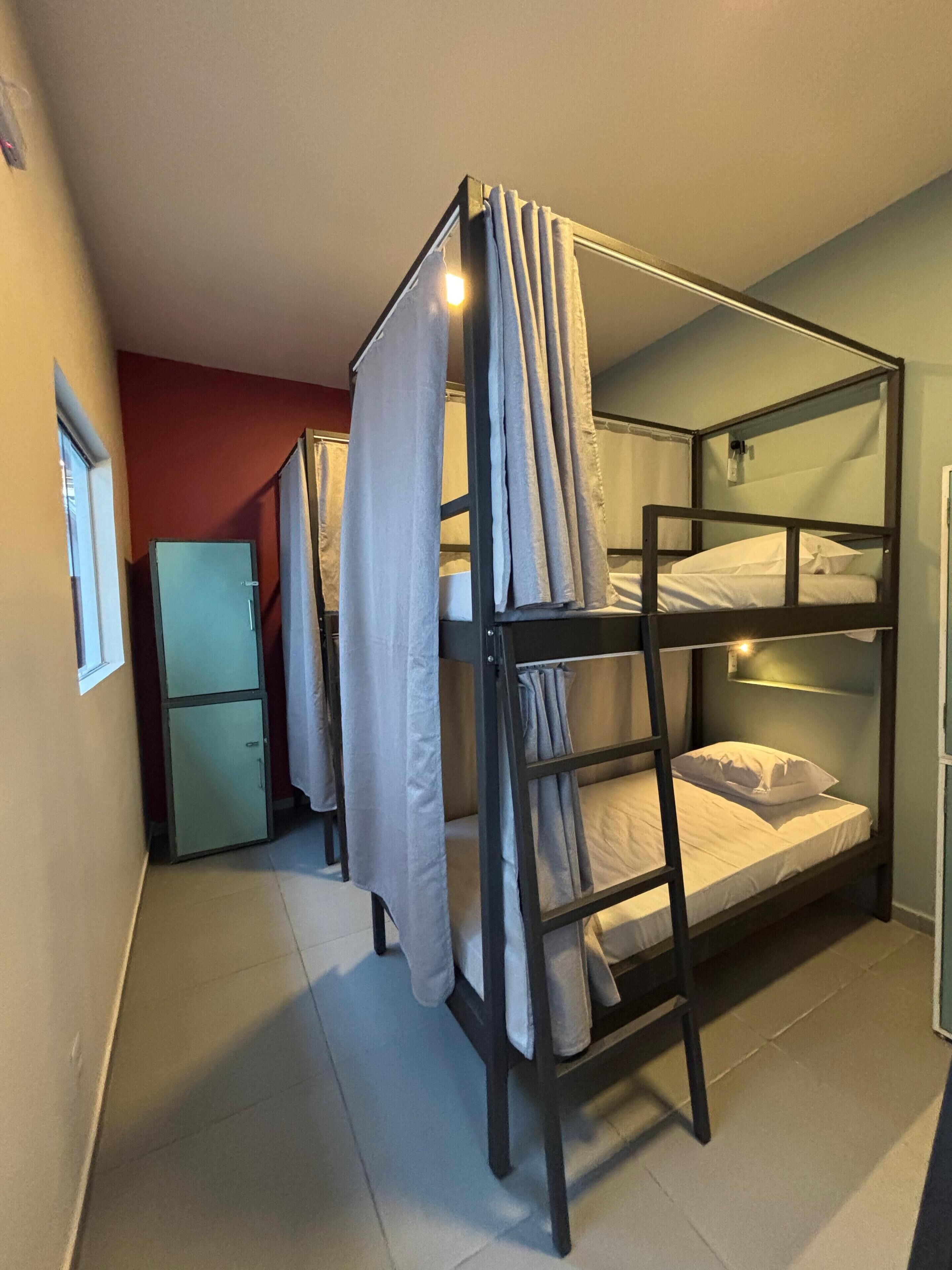 A bunk bed room with a small refrigerator and curtains.