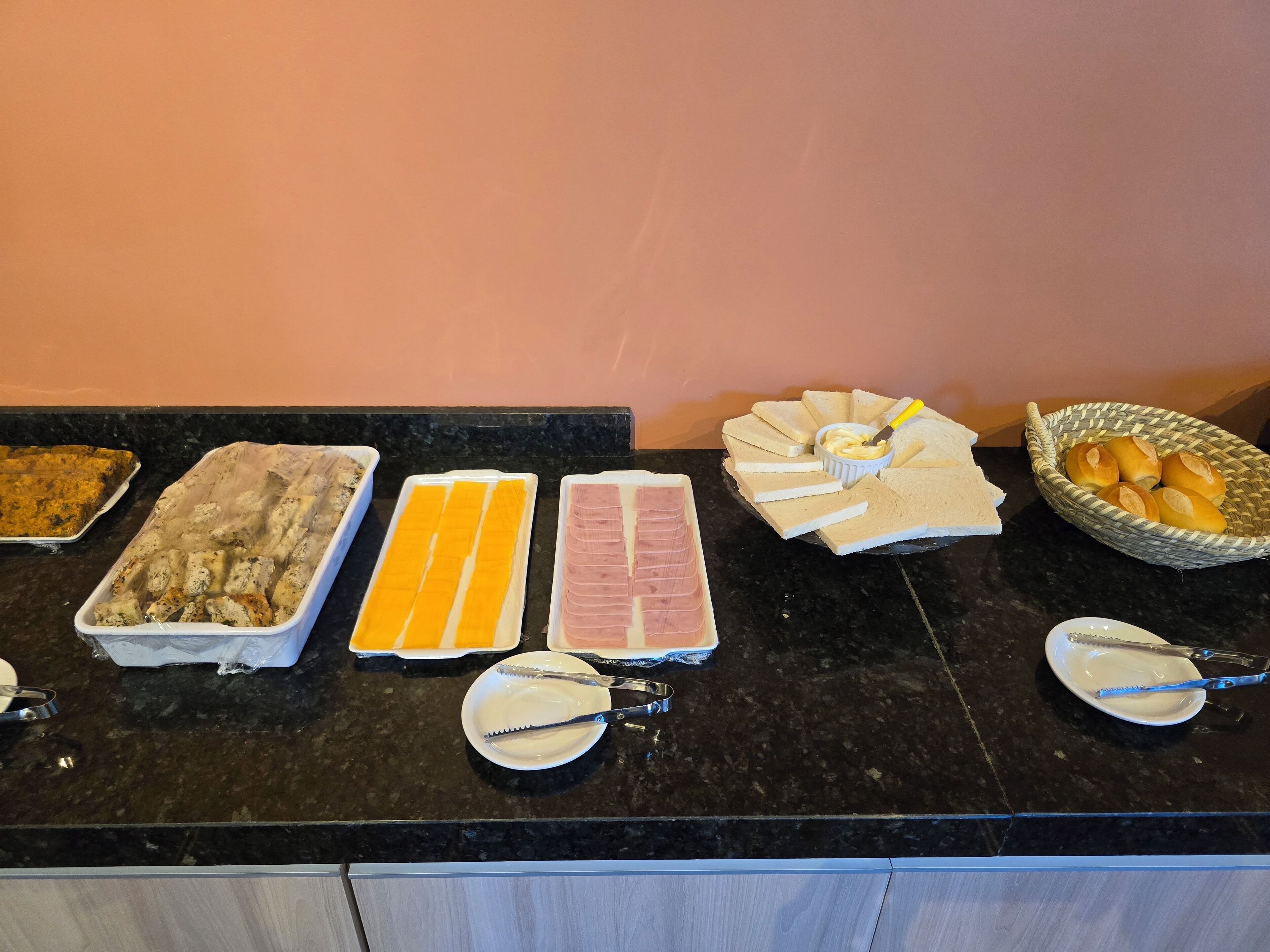 A buffet table with various food items including bread, cheese, and meats.