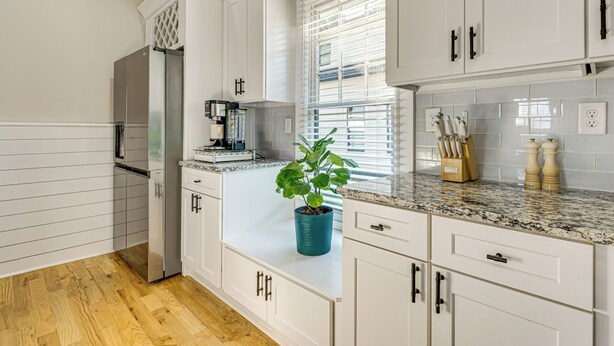 A modern kitchen with white cabinetry, a stainless steel refrigerator, a coffee machine, and a potted plant on the countertop. - Walk to Beltline: Wfh-friendly Hub w/ Yard! (Atlanta)