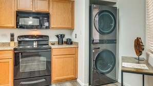 A compact kitchen with wooden cabinets, a microwave, an oven, and a front-loading washer. - 3 Mi to Talking Stick: Condo w/ Community Perks! (Scottsdale)