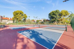 Ein Tennisplatz mit mehreren Spielfeldern, umgeben von Bäumen und Gebäuden.
