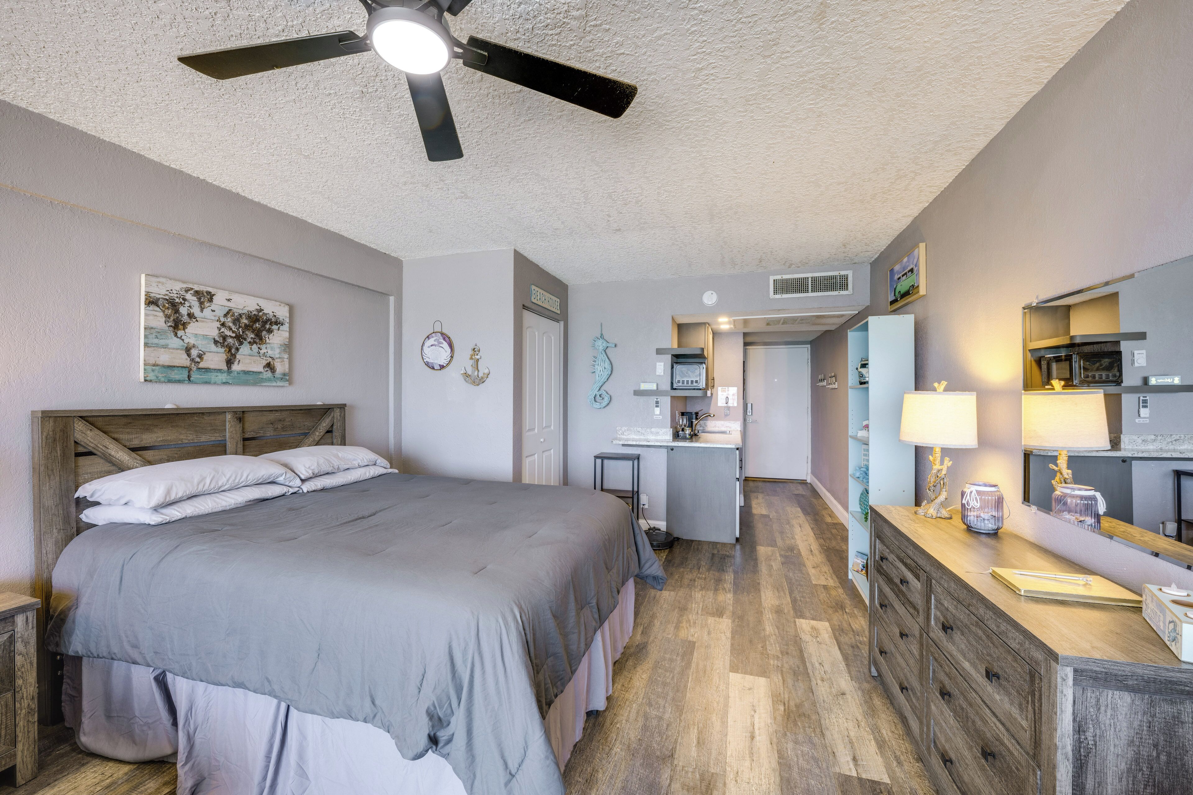 Une chambre comprenant un lit, un ventilateur de plafond, un coin cuisine et une salle de bain.
