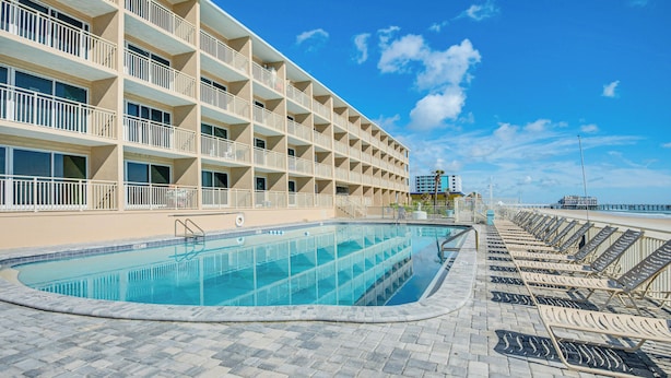 A hotel with a swimming pool, outdoor seating, and a view of the beach. - Oceanfront Gem - Walk to Daytona Beach Pier! (Daytona Beach)