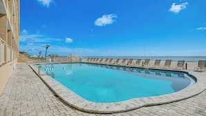 A swimming pool with a curved edge, adjacent to a beach. - Oceanfront Gem - Walk to Daytona Beach Pier! (Daytona Beach)