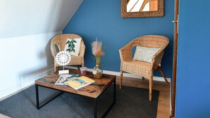 A room with two wicker chairs, a coffee table, and a blue accent wall.