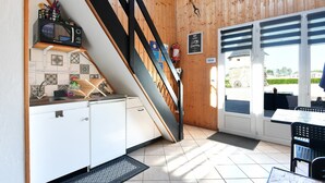 Eine Küche mit Mikrowelle, Spüle und Schränken, eine Treppe und ein Essbereich mit Tisch und Stühlen.