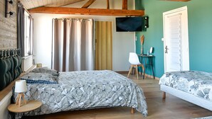 Ein Schlafzimmer mit zwei Betten, einem Fernseher, einem Schreibtisch und einem Sessel.