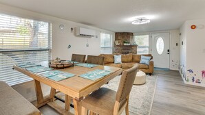 A modern living room with a wooden dining table, a sofa, and a kitchen area in the background. - 3 Mi to Apollo Beach Preserve: Family Retreat! (Apollo Beach)