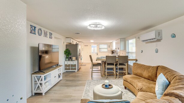 A modern living room with a brown sofa, a TV, and a dining area in the background. - 3 Mi to Apollo Beach Preserve: Family Retreat! (Apollo Beach)