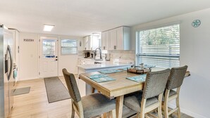 A modern kitchen with a dining area, wooden flooring, and a view of the outdoors through large windows. - 3 Mi to Apollo Beach Preserve: Family Retreat! (Apollo Beach)