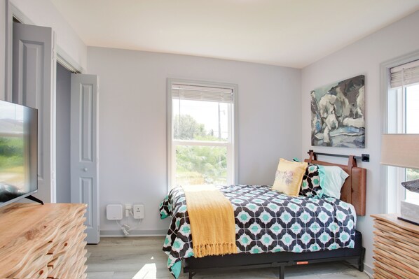A bedroom with a bed, a television, a window, and a painting on the wall. - Sunny Fort Myers Home: Golf, Shop & Relax! (Fort Myers)