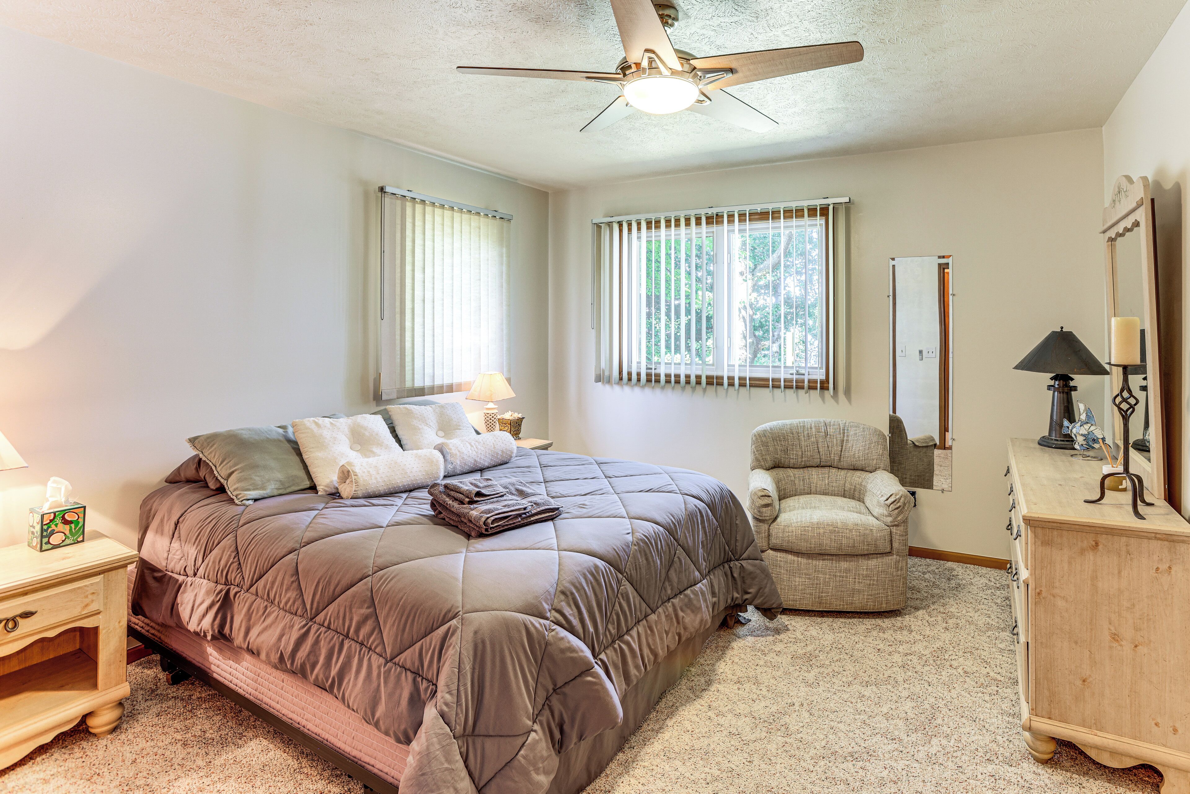 A bedroom with a bed, a chair, a dresser, and a ceiling fan.