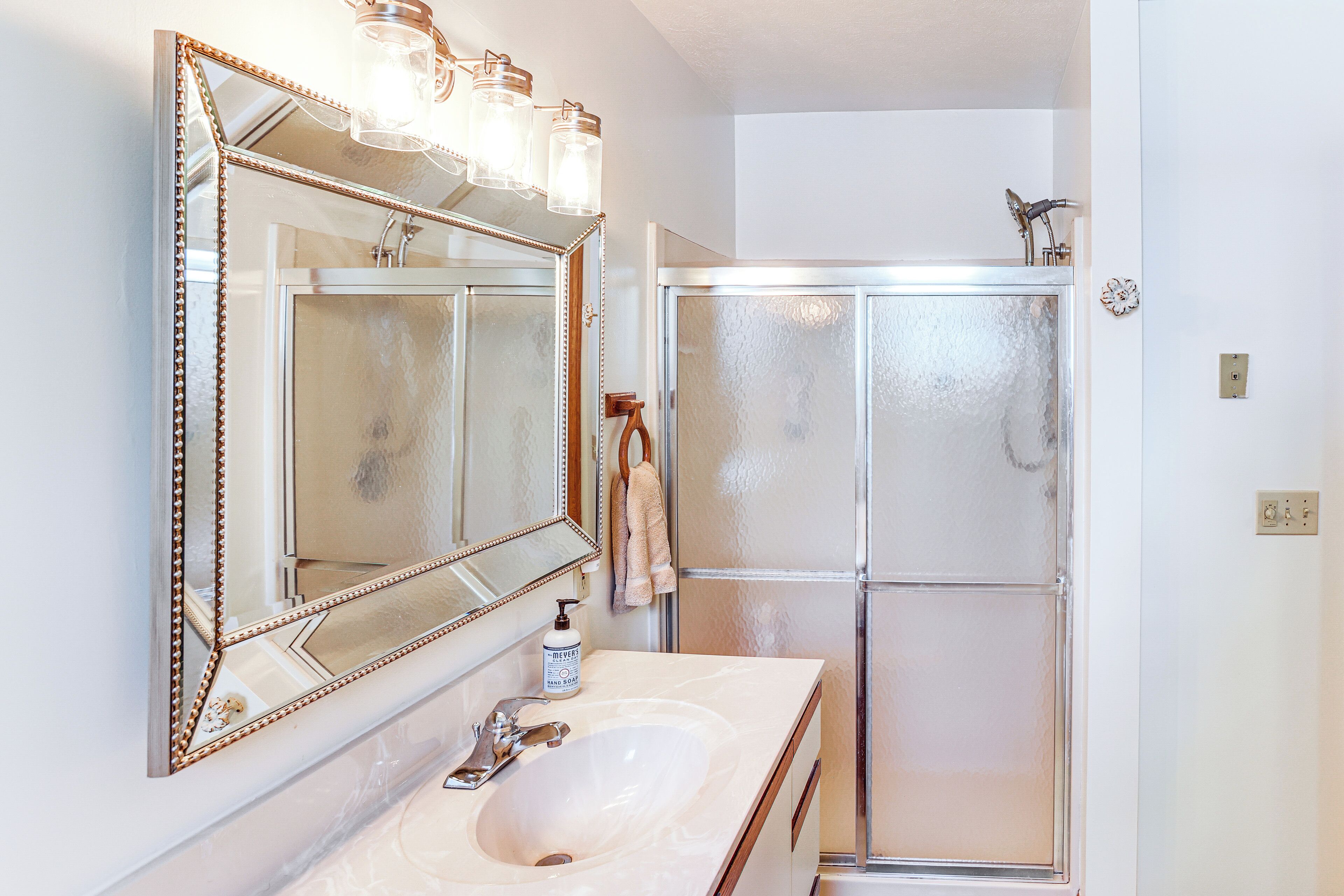 Un baño con un espejo grande, un lavabo y una ducha con cerramiento de vidrio.