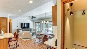 Une cuisine moderne avec un plancher en bois, un coin repas avec une table ronde et des chaises, et un salon avec un canapé et un téléviseur.