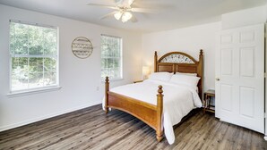 Une chambre à coucher avec un lit en bois, des murs blancs et un ventilateur de plafond.