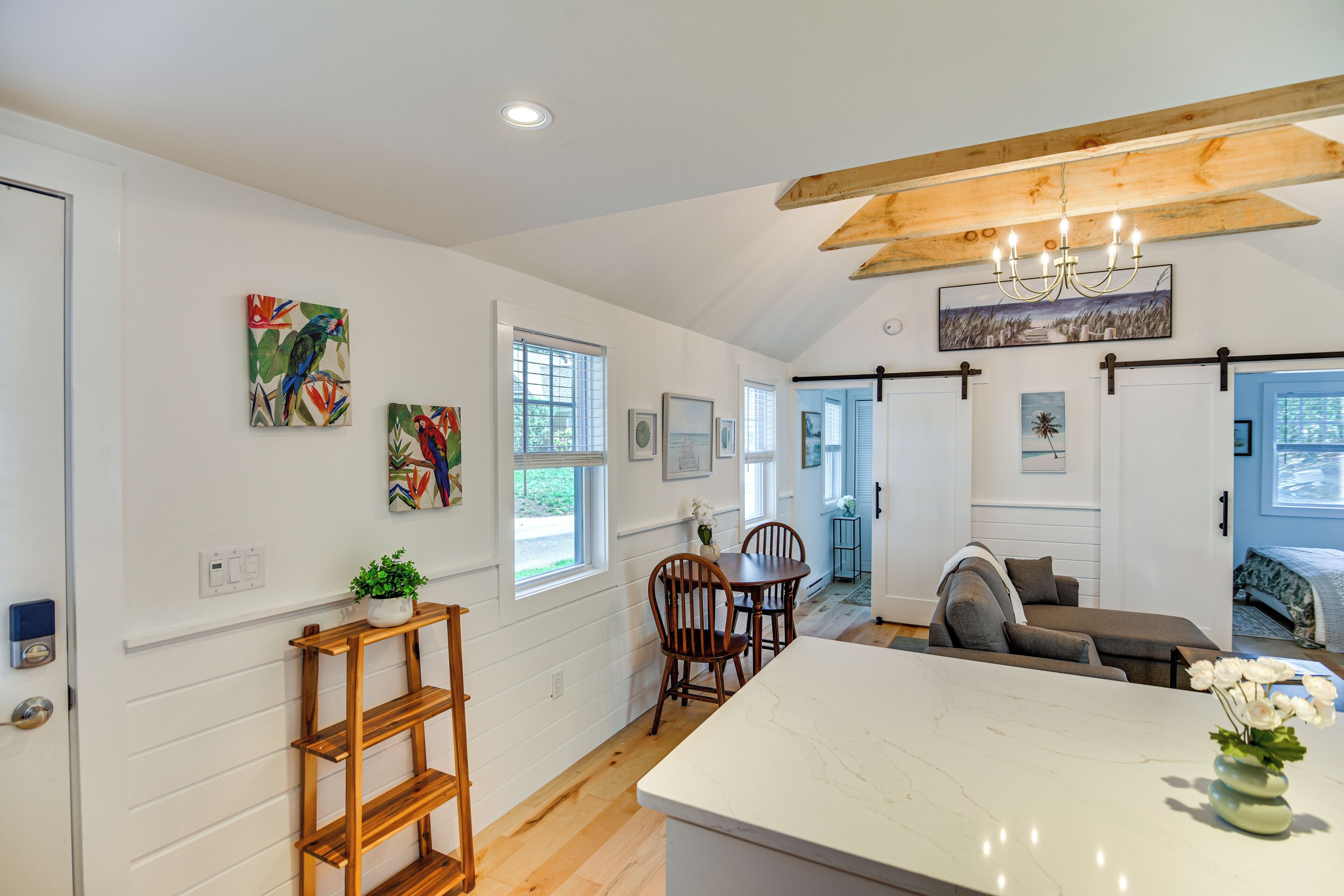 A modern kitchen with white cabinetry, a wooden island, and a dining area with a table and chairs.