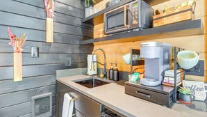 Una cocina moderna con microondas integrado, cafetera y pileta.