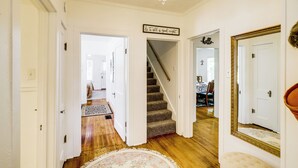 A hallway with a carpeted floor, a staircase, and a chandelier.